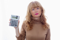 A woman unhappily holding up a calculator with a negative total on it