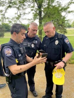 Image shows three Olathe police officers looking at phones