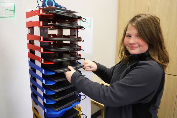 Image shows a girl unplugging device from PowerGistics charging Tower