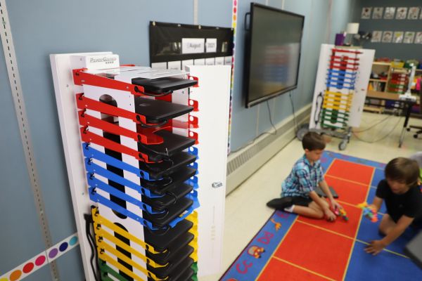 Image shows two PowerGistics charging stations in classroom and students playing on floor