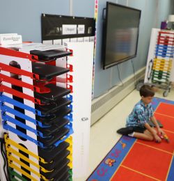 Images show two PowerGistics charging stations in classroom and students playing on floor