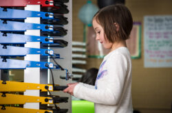 Image shows girl taking device out of PowerGistics charging Tower