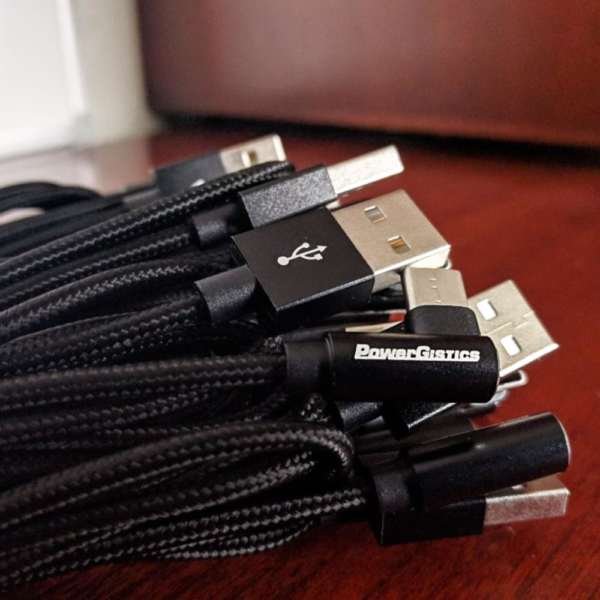 Image shows a bunch of PowerGistics black USB-A to USB-C cables sitting on a table